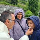 Don Isidoro Mercuri Giovinazzo offre la comunione a un bimbo sul sagrato di Lourdes