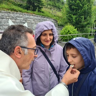 Don Isidoro Mercuri Giovinazzo offre la comunione a un bimbo sul sagrato di Lourdes