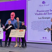 Liana Grange riceve il premio sul palco di Slow Wine; sullo sfondo, il volto di Gualtiero Crea